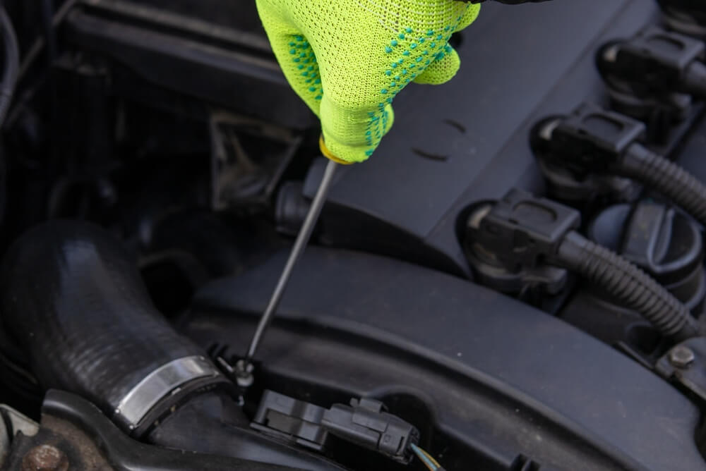 Person checking engine oil level with a dipstick
