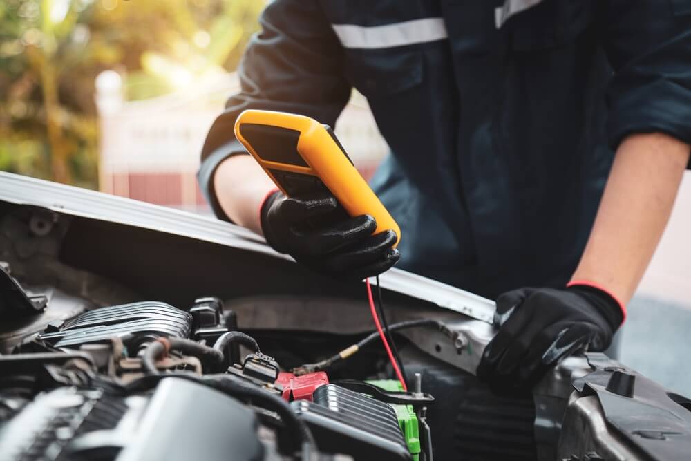 Mechanic using a voltmeter to check a car's starting system voltage